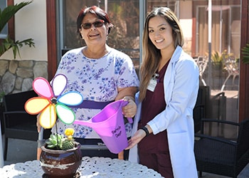 resident and nurse watering plant together