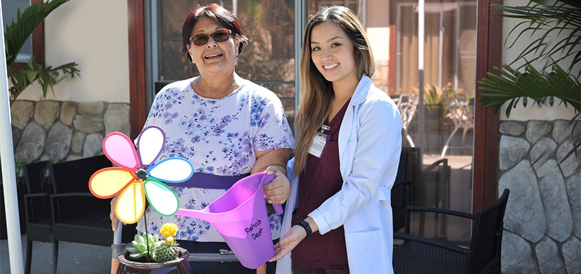 resident and nurse watering plants together
