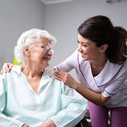A nurse leaning in to smile at a patient.