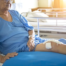 A patient in bed with dressings on his wounds.