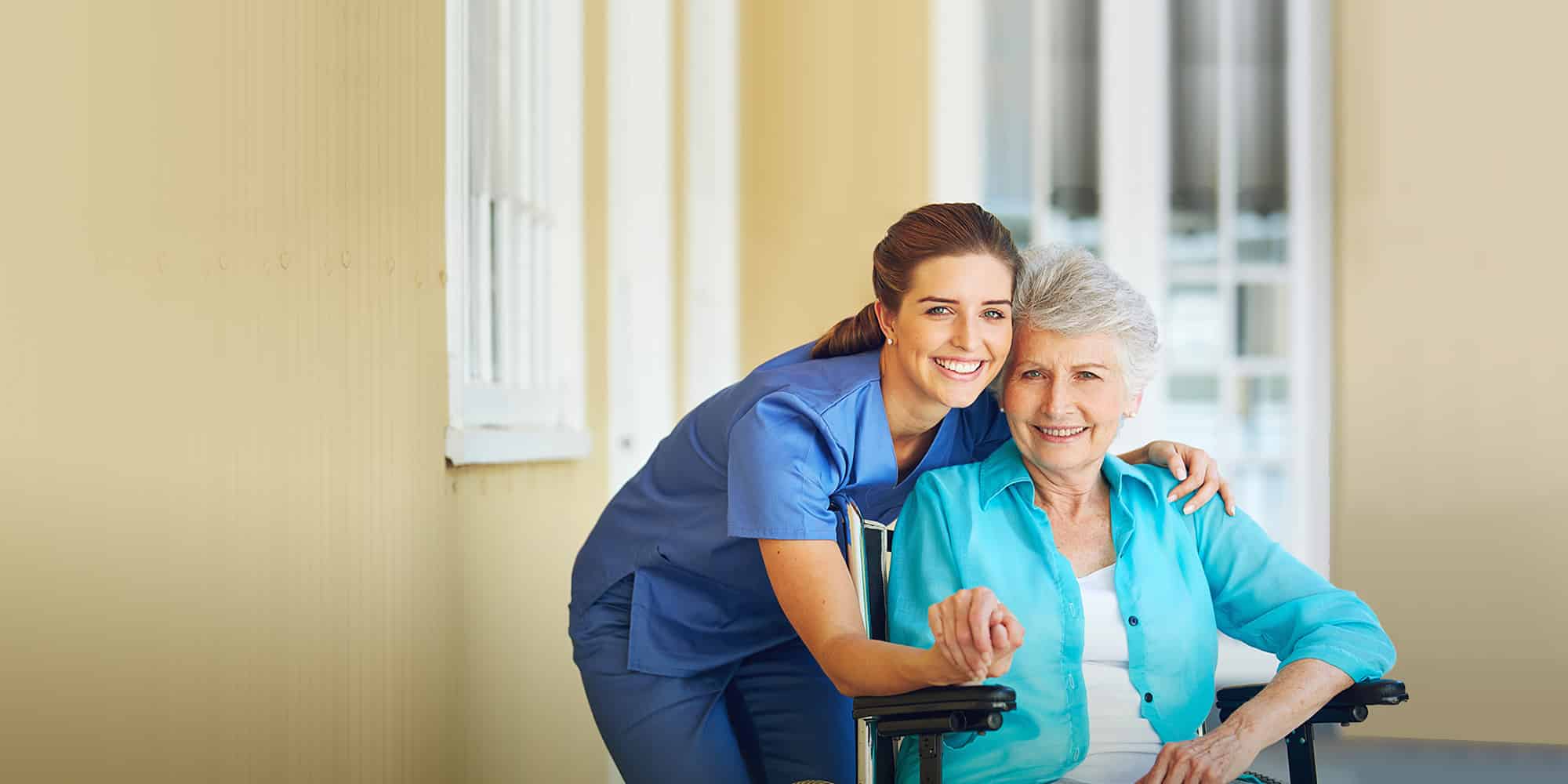 Ann elderly lady in a wheelchair smiling with a caregiver