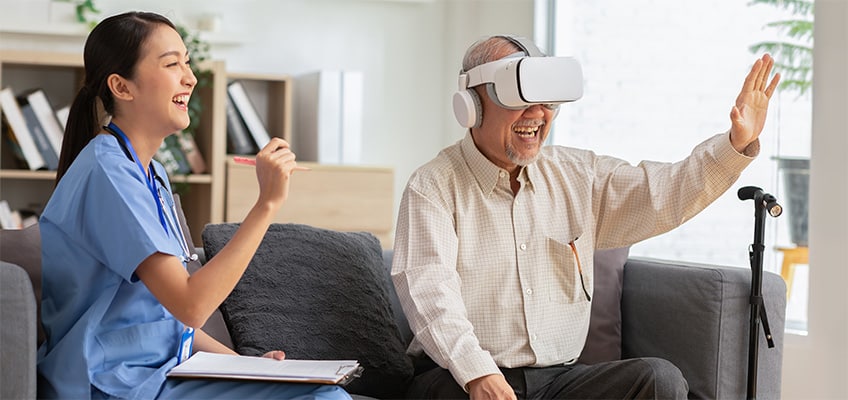 Older man playing a video game on a VR headset next to a nurse